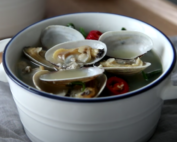 spinach clam soup in a white bowl with blue lining with handles